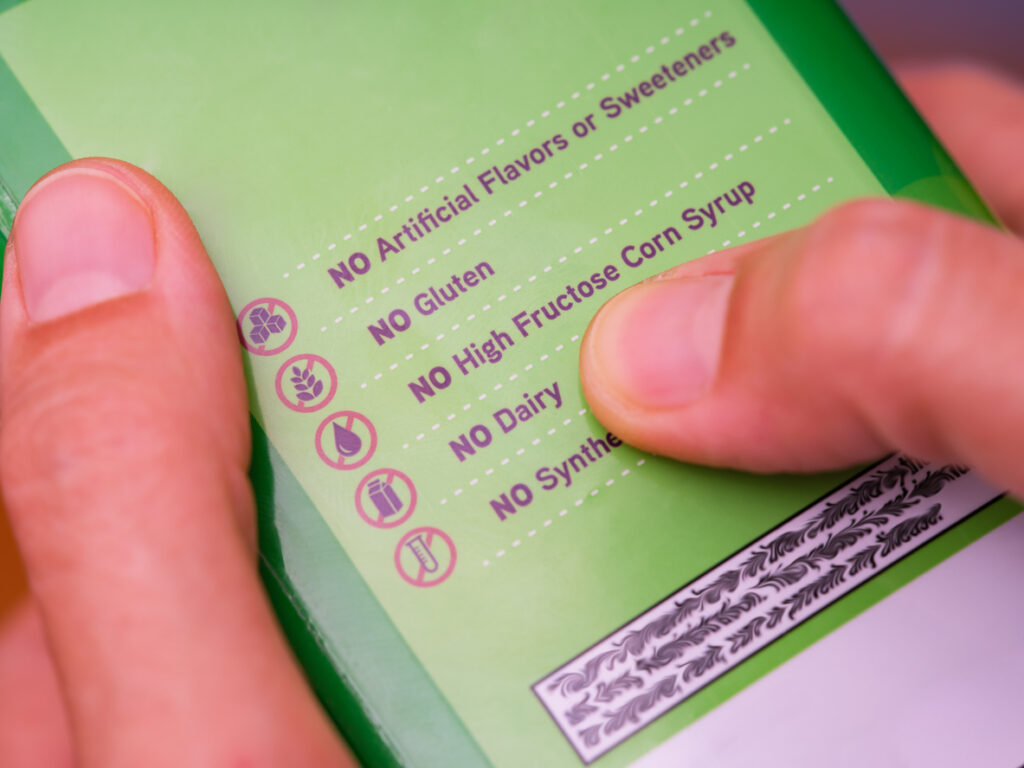 how to read nutrition labels A woman reading a label with the words No Artificial Flavors or Sweeteners, No gluten, No high fructose corn syrup, No dairy, No synthetics.