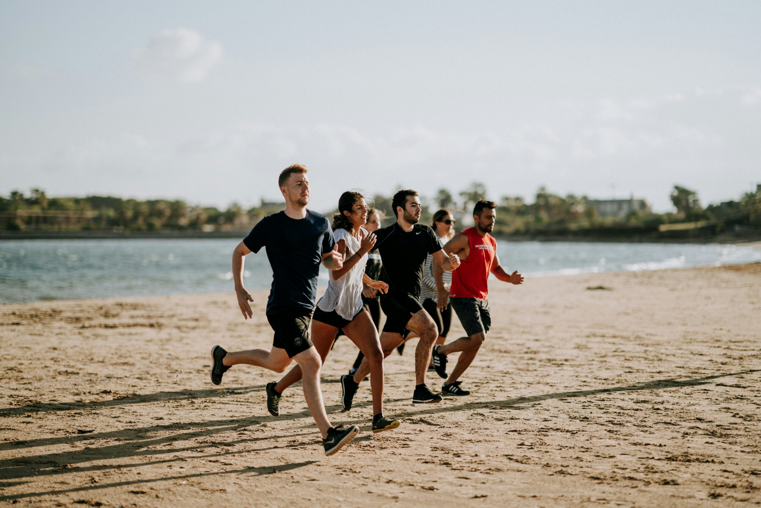 people running on the beach summer working out running shoes for calf pain