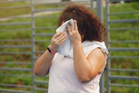 heat related illnesses woman wiping her forehead outdoors