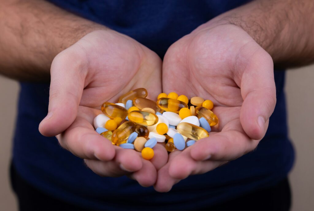 man holding a ton of supplements vitamins and minerals best omega-3 supplements for brain and heart health
