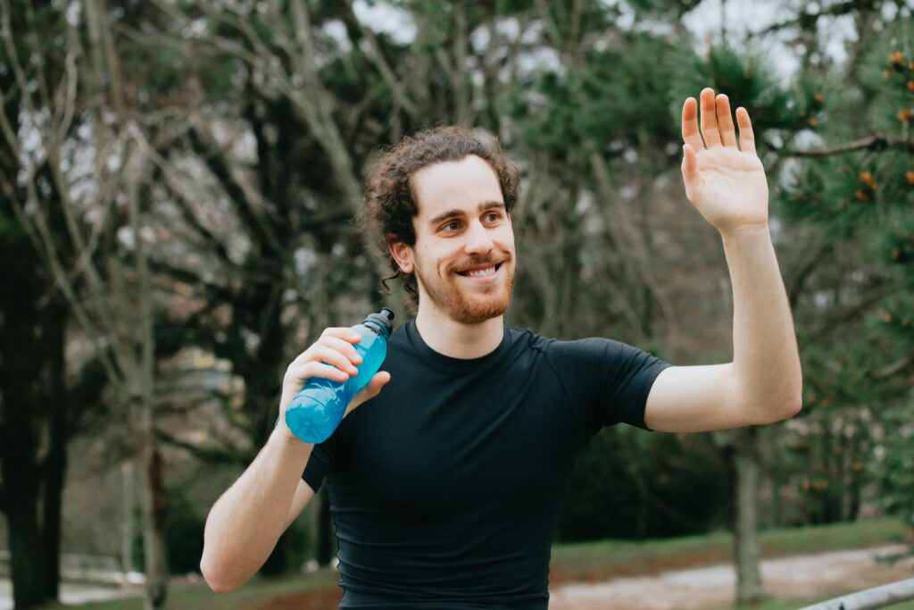man waving after an outdoor workout hydration products for summer workouts