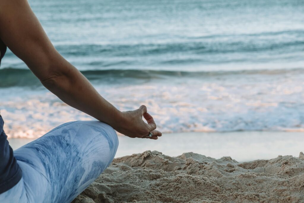 woman meditating on the beach meditation Photo by <a href="https://unsplash.com/@chelseacgates?utm_source=unsplash&utm_medium=referral&utm_content=creditCopyText">Chelsea Gates</a> on <a href="https://unsplash.com/photos/person-in-blue-shorts-sitting-on-beach-shore-during-daytime-n8L1VYaypcw?utm_source=unsplash&utm_medium=referral&utm_content=creditCopyText">Unsplash</a>