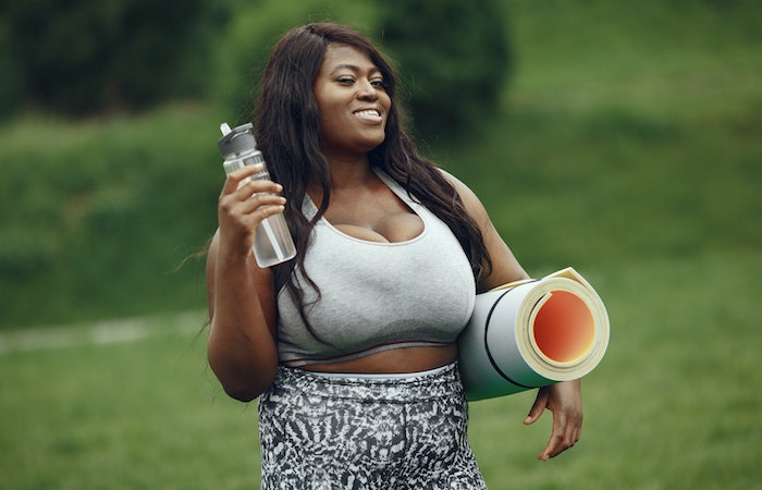 Woman holding water bottle and yoga mat - Tabata workout