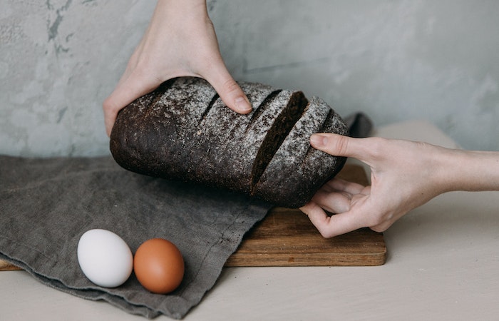 hands of person breaking bread