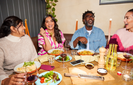 people laughing and smiling around a dinner table - seasonal fitness