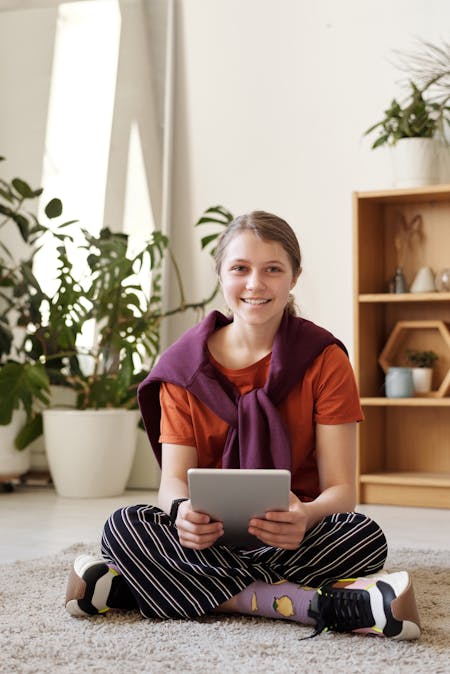 mental health for teens girl holding tablet and looking at the camera, smiling