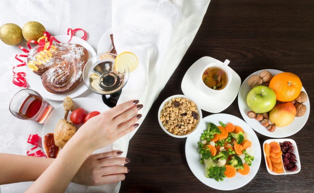 holiday detox holiday recovery Table with healthy and unhealthy food and alcohol. Woman hands covering the part with harmful dishes and drinks with table cloth. Dieting after Christmas and New Year celebration.